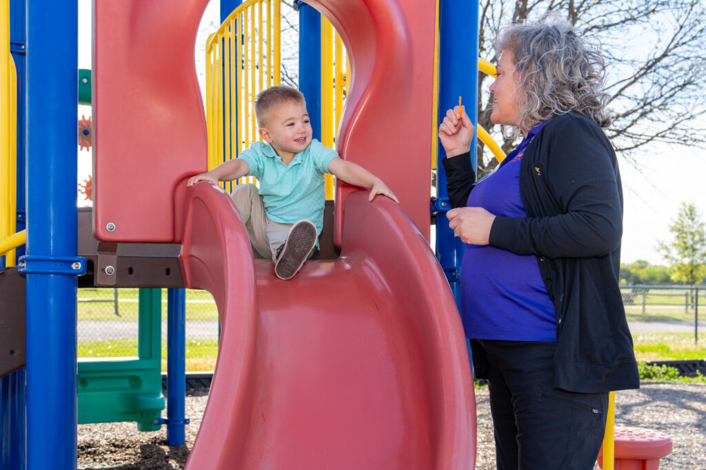 Therapist blows bubbles with child on slide