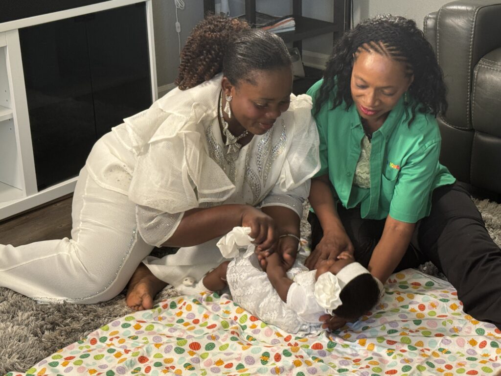 two women play with infant on floor of home